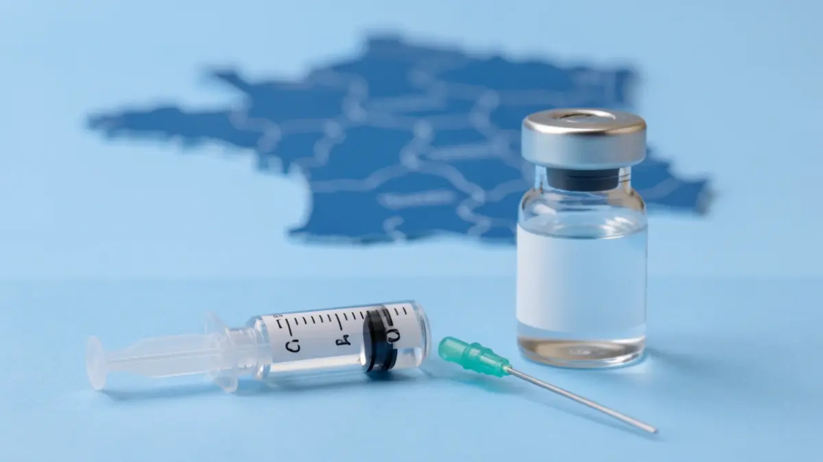 Generic image of a medical syringe and a vaccine vial on a blue background, with abstract shapes suggesting a map of the Auvergne-Rhône-Alpes region.